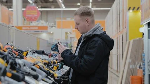 A man in a hardware store chooses electrical goods. The buyer in the store Stock Photos