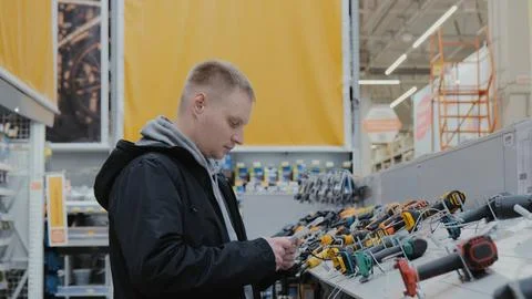 A man in a hardware store chooses electrical goods. The buyer in the store Stock Photos