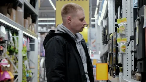 A man in a hardware store chooses a wood-burning stove. Buying a wood-burning Stock Footage 253314440
