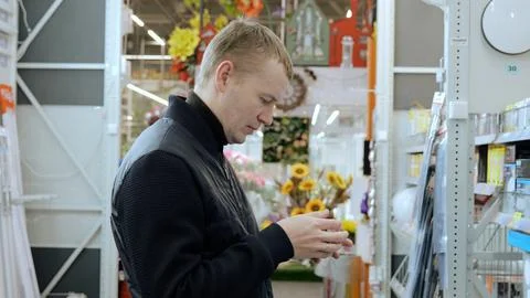 A man in a hardware store choosing a light bulb. translator: good price. Shopper Stock Photos