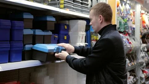 A man in a hardware store choosing a tool. Handyman is choosing a toolbox in a Foto stock