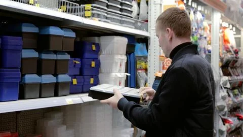 A man in a hardware store choosing a tool. Handyman shops for toolboxes at a Stock Photos