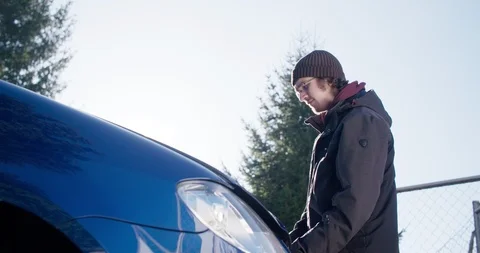 Man has broken down  his car and checks under his bonnet for issues 動画素材 104982321