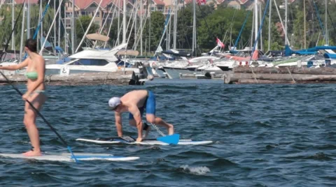 Man has difficulty standing on paddle board  Stock Footage 44824466