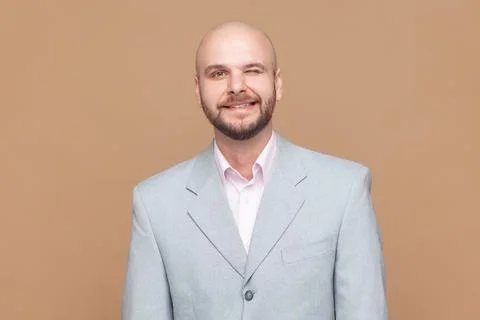 Man has fun and winks eye, smiles with teeth makes funny grimace, wearing gray Stock Photos