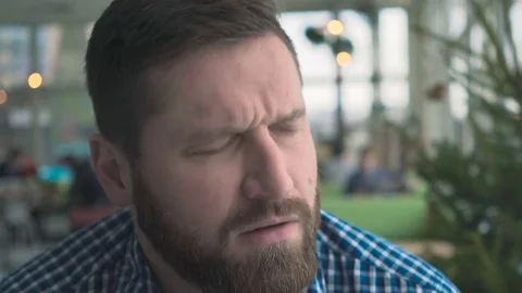 Man has a headache, portrait, in cafe, very close steadicam shot  库存影片 72952307