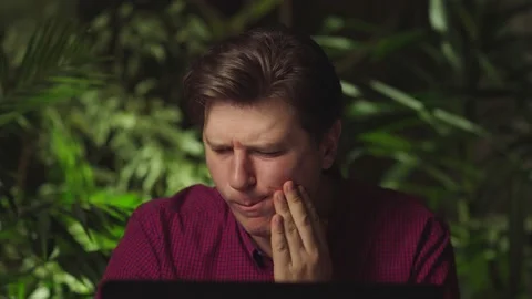 A man has a pain in his teeth while working at a computer Stock Footage 149041336