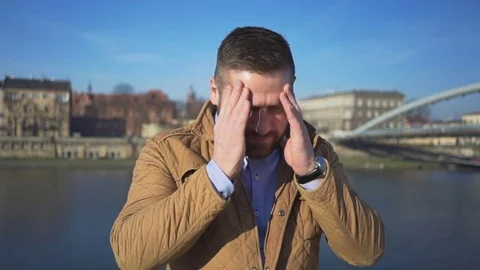 Man has painful headache on the background of the river, sunny day 库存影片 72709503