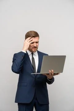 Man has problems in business, poor financial results looking at laptop on grey Stock Photos