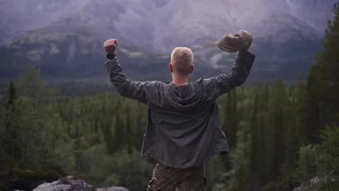 A man has reached the top of a mountain and is incredibly happy about it Stock Footage 166608782