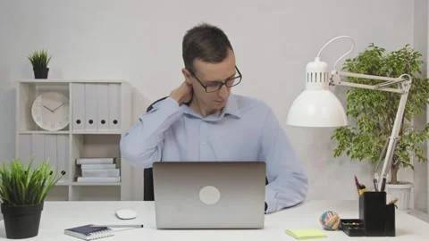 A man has a sore neck after hard work at a table with a laptop. pain in the neck Stock Footage 149040182