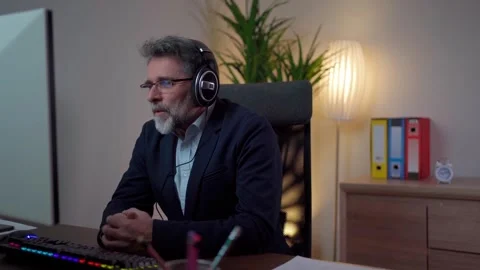 Man has a video call via webcam in the office while using headphones Video stock 268328039