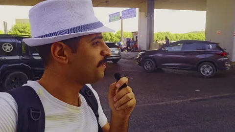 A man with a hat and a backpack eating a hot dog Stock Footage 292231695
