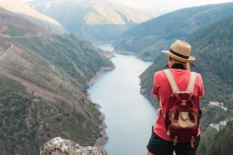 Man with hat and backpack taking photo of mountain landscape with river on su Stock Photos