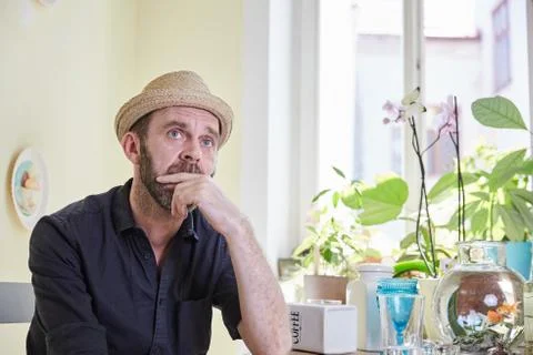 Man with hat and beard sitting and pondering Stock Photos