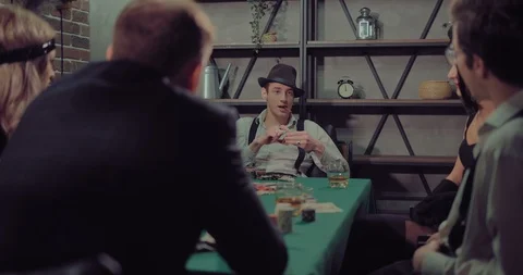 Man with a hat and a cigar sits at a green poker table. Chips and cards are on Stock Footage 105881838
