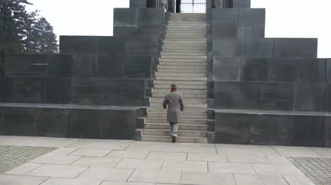 Man with the hat and coat climbing the stairs of the monument Stock Footage 47932395