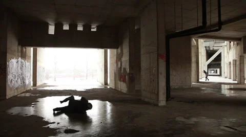 Man in the hat and coat rolling on the ice in an abandoned urban building Stock Footage 48020125
