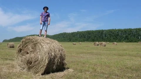A man in a hat and glasses is dancing on a bale of hay. Stock Footage 135458307