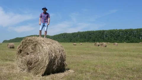 A man in a hat and glasses is dancing on a bale of hay. Stock Footage 135458318