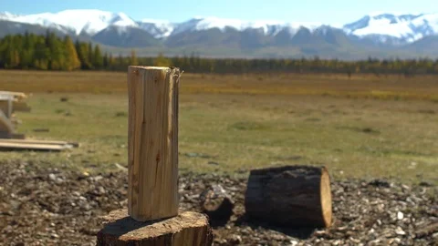 Man in hat with axe chopping firewoods in mountains. Guy with axe Stock Footage 101275395