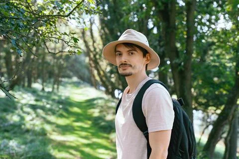 Man In Hat With Backpack Hiking In Forest Trail Fotos de archivo