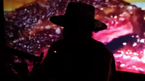 A man in a hat with a beard sits at a table, smokes a cigar, pours alcohol into Stock Footage 241501190