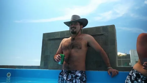 A man with a hat being surprised by the exit of cold water from a pool in a pool Stock Footage 173506424