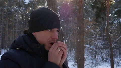 The man in the hat breathes on hands in winter forest Stock Footage 72128129
