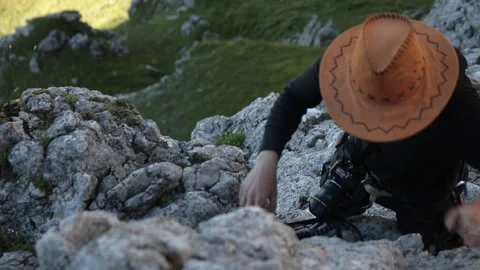 A man in a hat climbs the mountain. Video stock 97762680