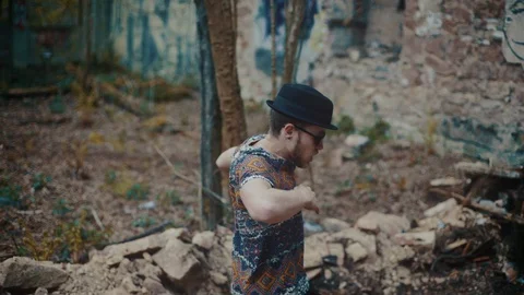 Man with hat dancing in between rubble of empty building Video stock 117916860
