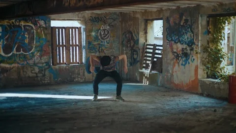 Man in hat dancing in empty building and looking straight at camera Stock Footage 117918166