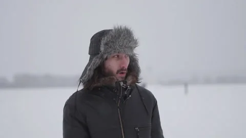 A man in a hat with earflaps in the snow Stock Footage 257891373