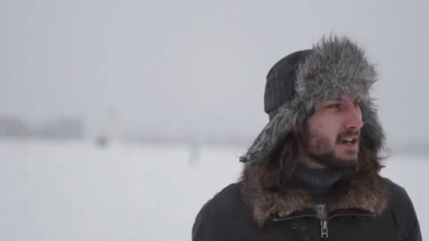 A man in a hat with earflaps in the snow Stock Footage 259293195