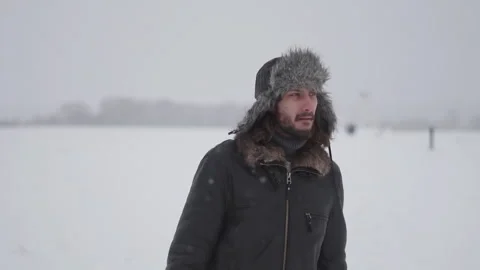 A man in a hat with earflaps in the snow Stock Footage 259689405