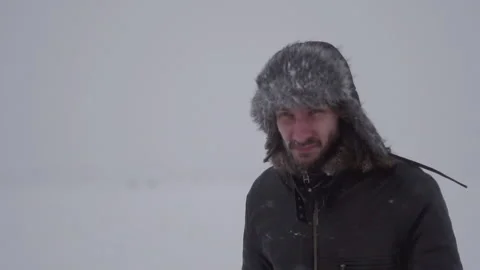 A man in a hat with earflaps in the snow Stock Footage 259689439