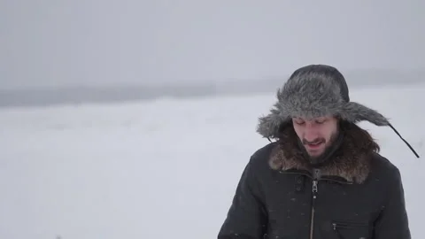 A man in a hat with earflaps in the snow Stock Footage 259689483