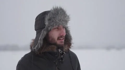A man in a hat with earflaps in the snow Stock Footage 260800628