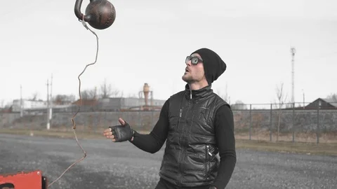 Man hat, glasses black clothes throws weight up on a sports field on the street. Stock Footage 126851266