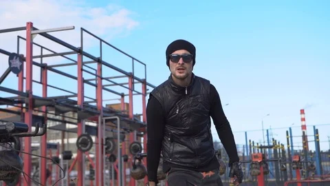 Man hat, glasses black clothes throws weight up on a sports field on the street. Stock Footage 126851474