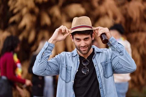 Man with hat looking at camera while holding a beer at an outdoor party. Foto stock