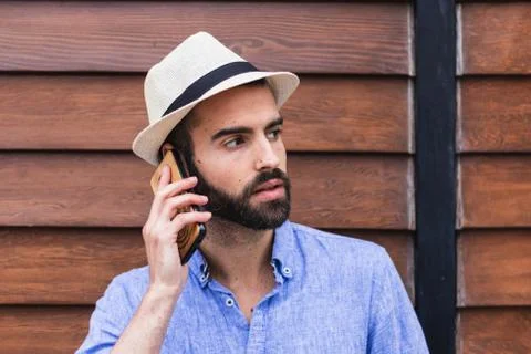 Man with hat making a call in front of a wooden wall Stock Photos