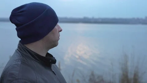 Man in Hat Smiling Looking at the River and Then Looks at us Turning His Head Stock Footage 73904301