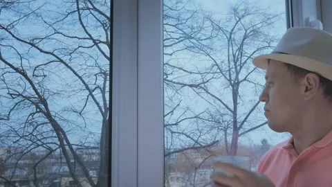 Man with the hat standing by the window watching what's going on outside, copy Stock Footage 162220743