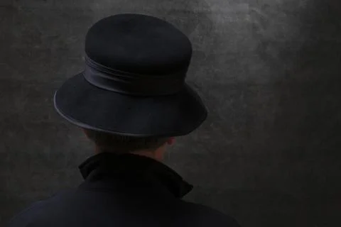 A man in a hat stands with his back against a dark background Fotos de archivo