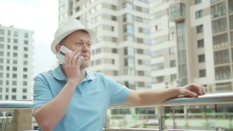 Man in a hat talking on a mobile phone, against the background of skyscrapers Stock Footage 154431632