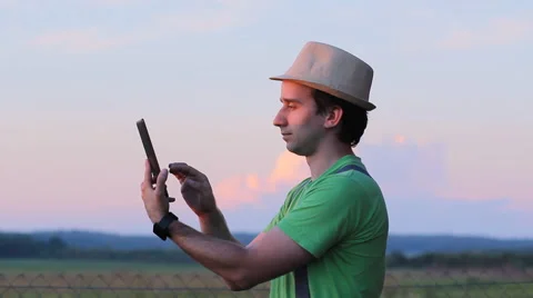 The man in the hat is touching the tablet. Against the backdrop of a beautiful Stock Footage 64777374