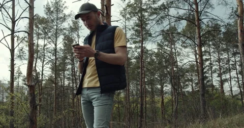 A man with a hat uses his mobile phone in the park. Stock Footage 138586870