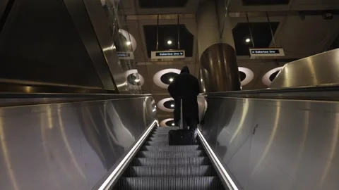A man in a hat is walking down a long escalator Stock Footage 297859838