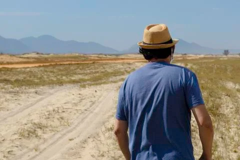 Man with hat walking through an area near the beach Stock Photos